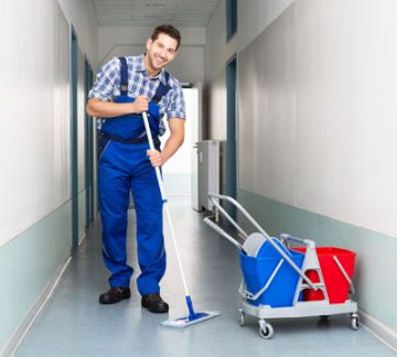 Happy Male cleaner with cleaning equipment's mopping floor